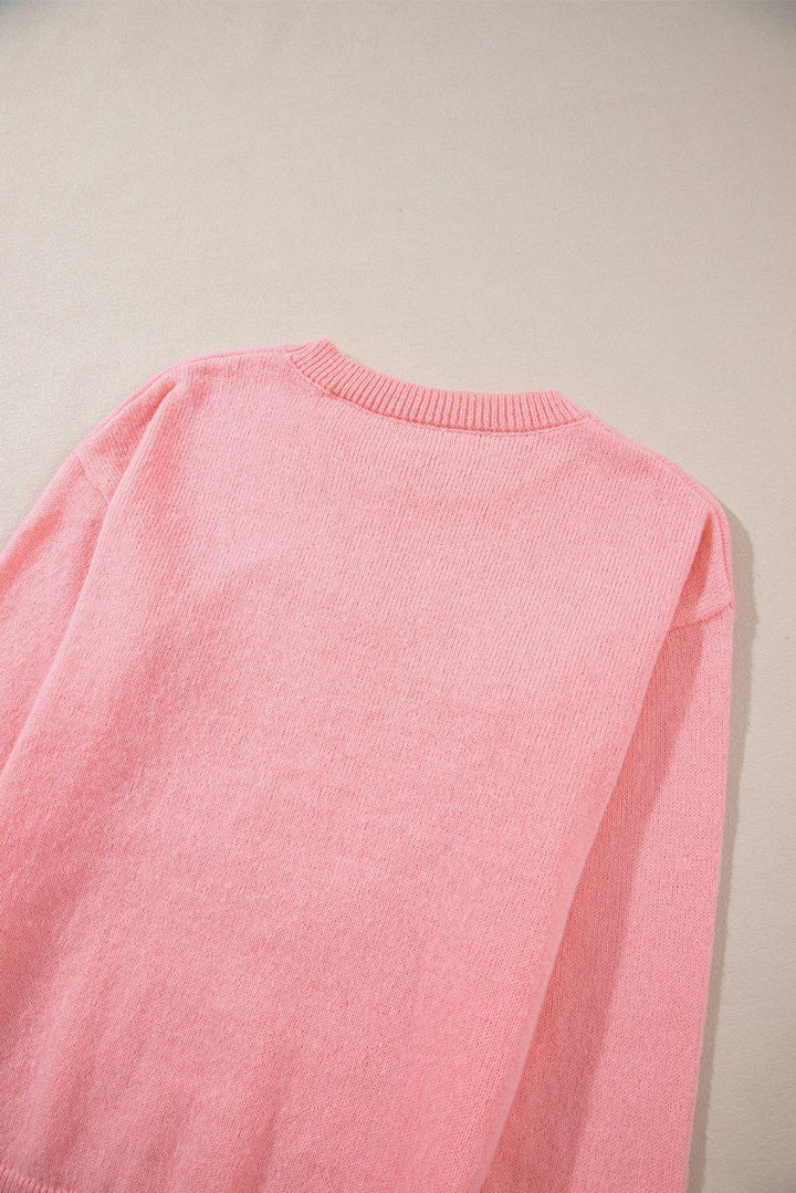 a pink sweater laying on a white surface