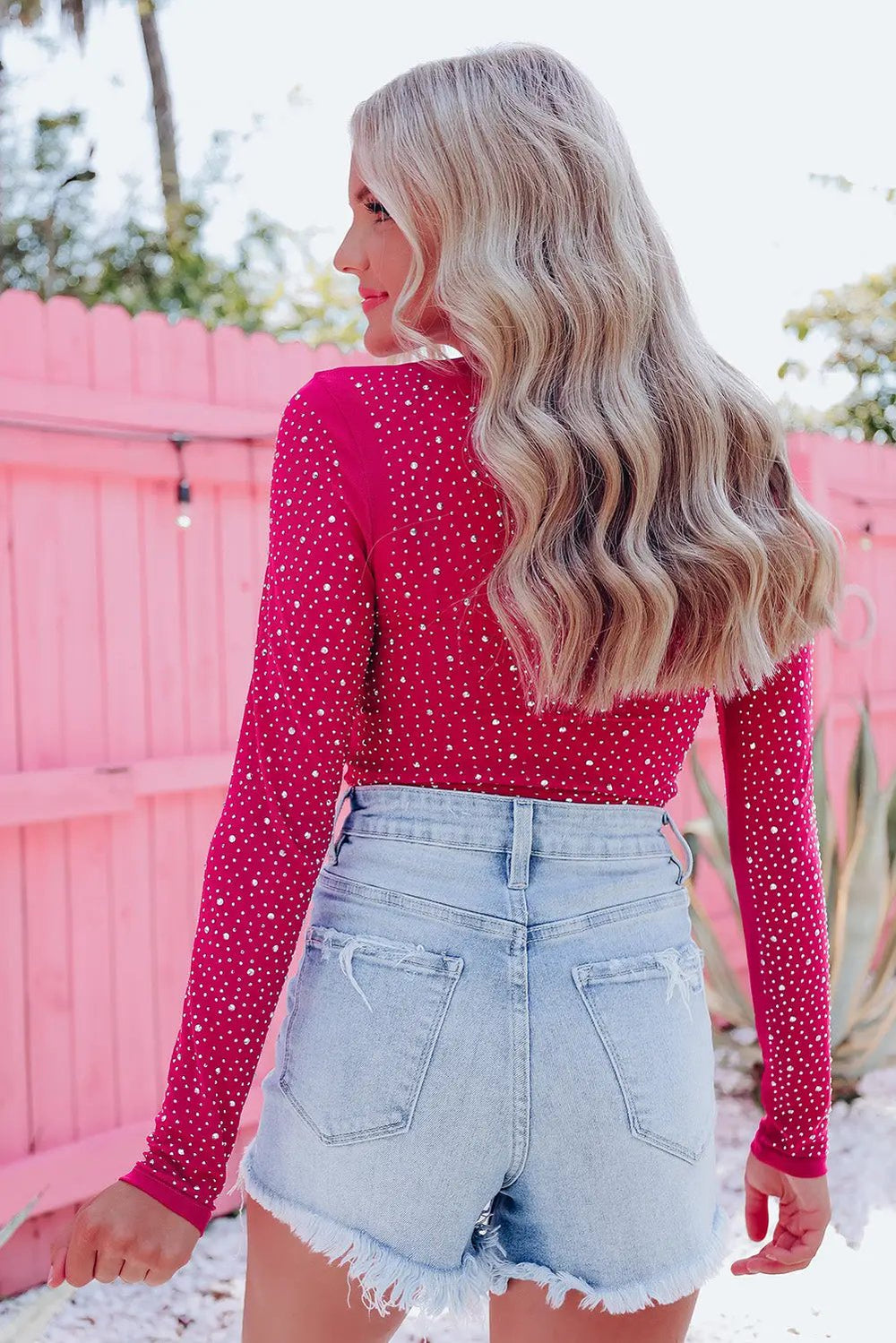 a woman in a pink top and denim shorts