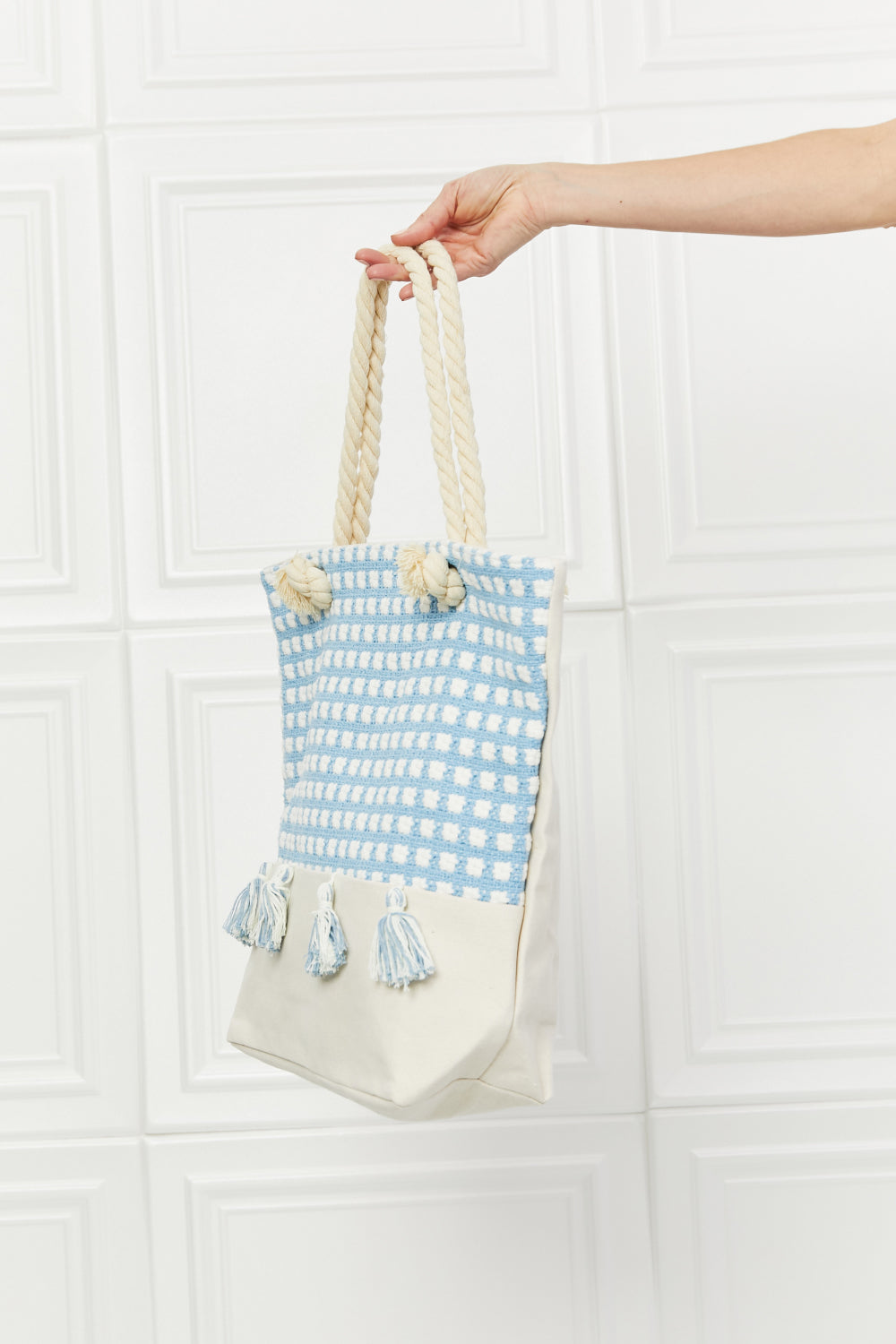 a hand holding a blue and white tote bag