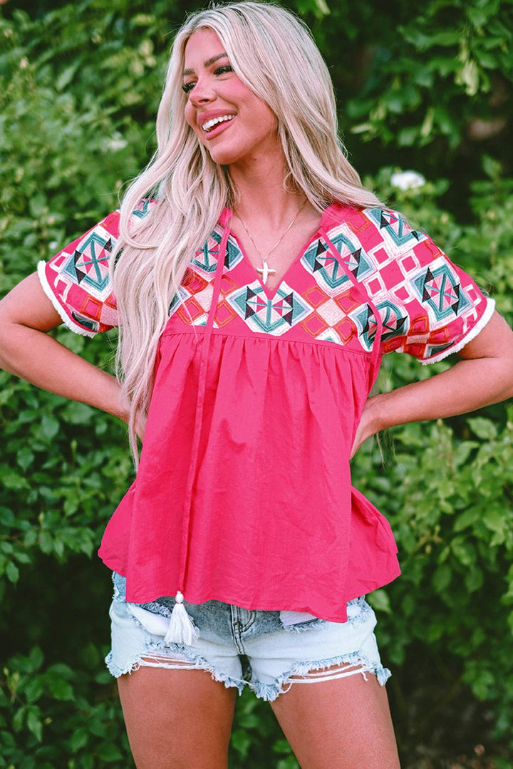 a woman wearing a red top and denim shorts