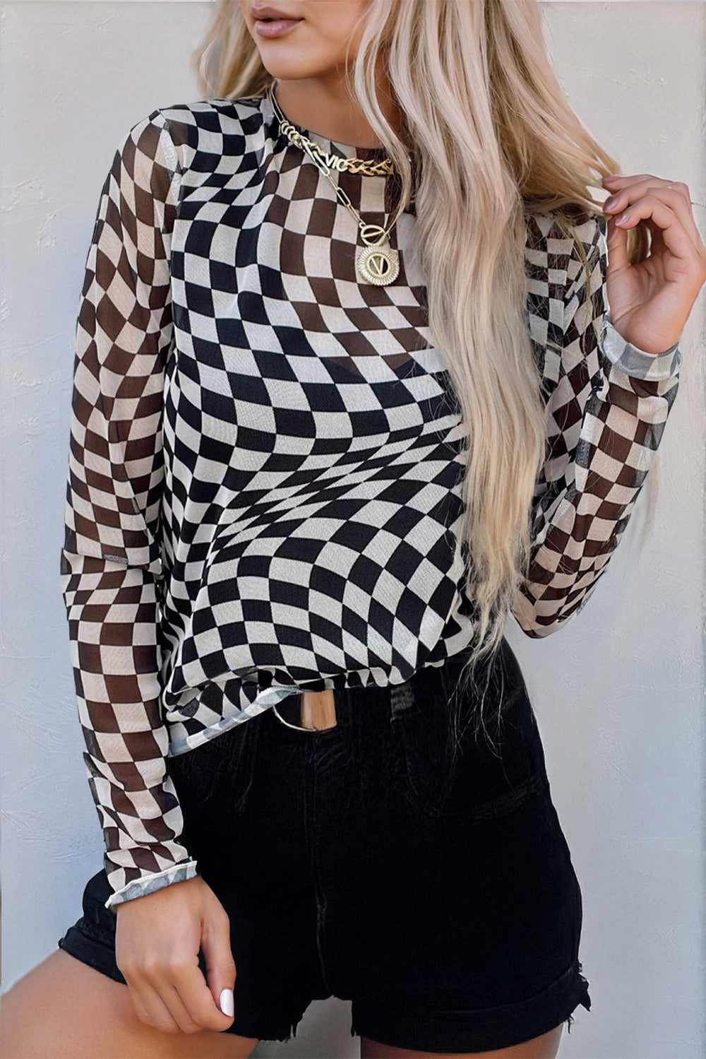 Model wearing the Rose Checkered Pattern Mesh Mock Neck Long Sleeve Top in black and white, styled with black shorts for a trendy western look.