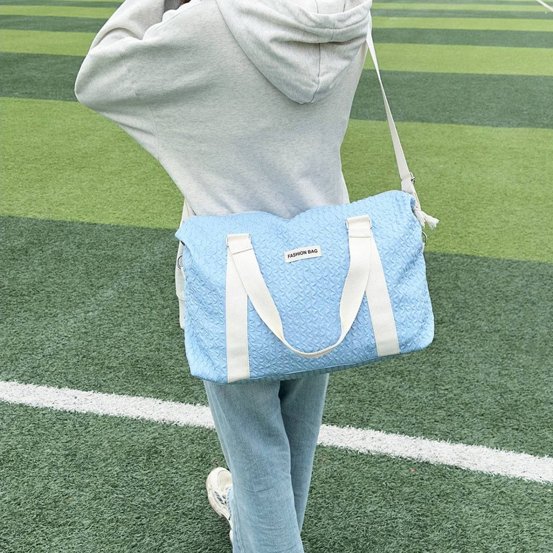 a woman holding a blue bag on top of a field