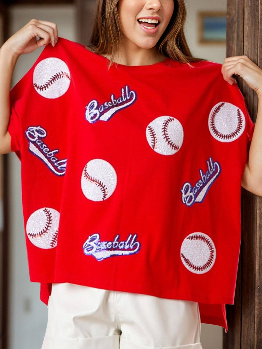 a woman wearing a red shirt with baseballs on it