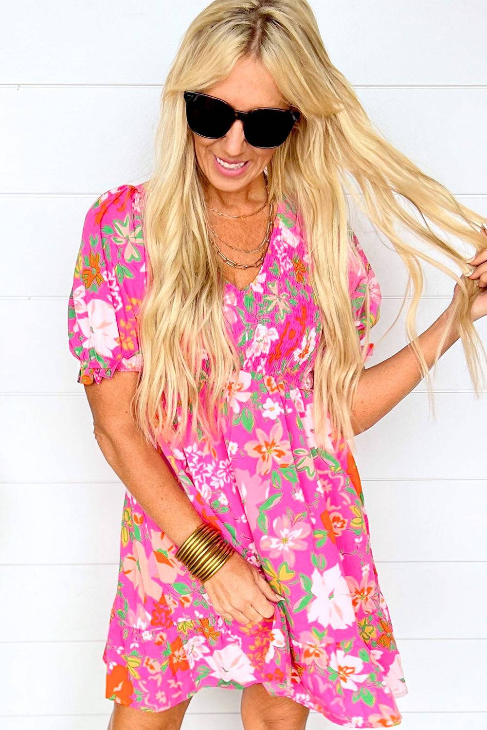 a woman with long blonde hair wearing a pink floral dress