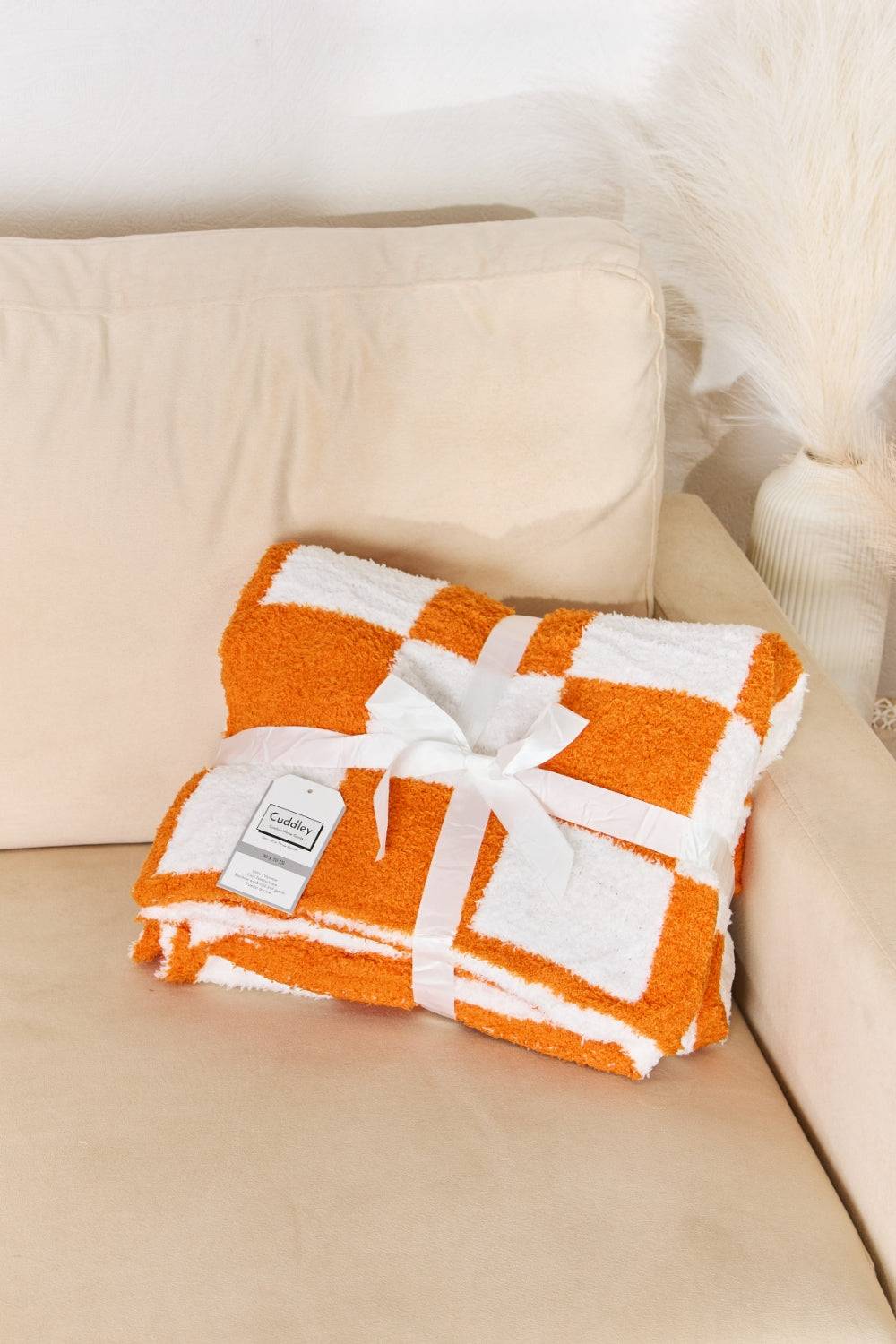 a white and orange blanket sitting on top of a couch