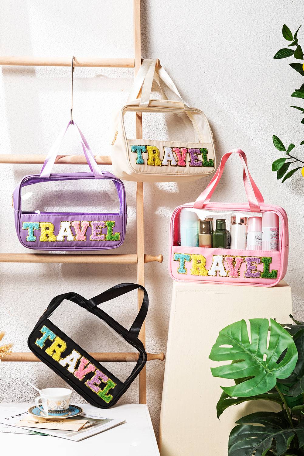 three travel bags hanging on a wall next to a potted plant