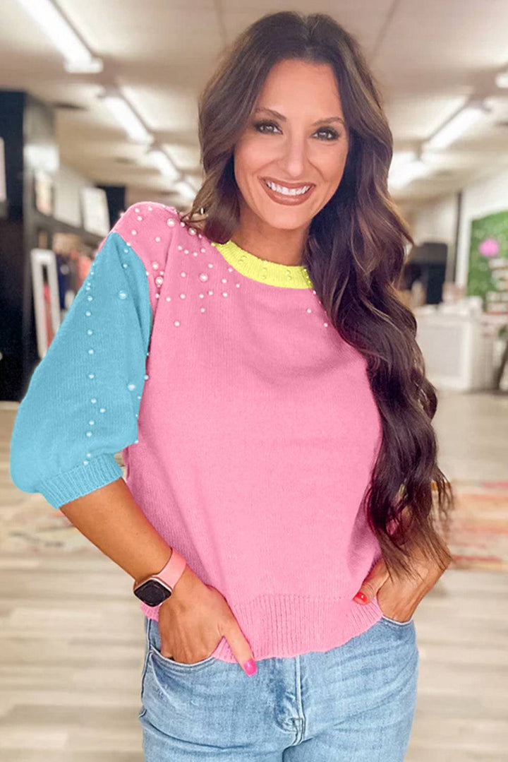 a woman wearing a pink and blue sweater and jeans