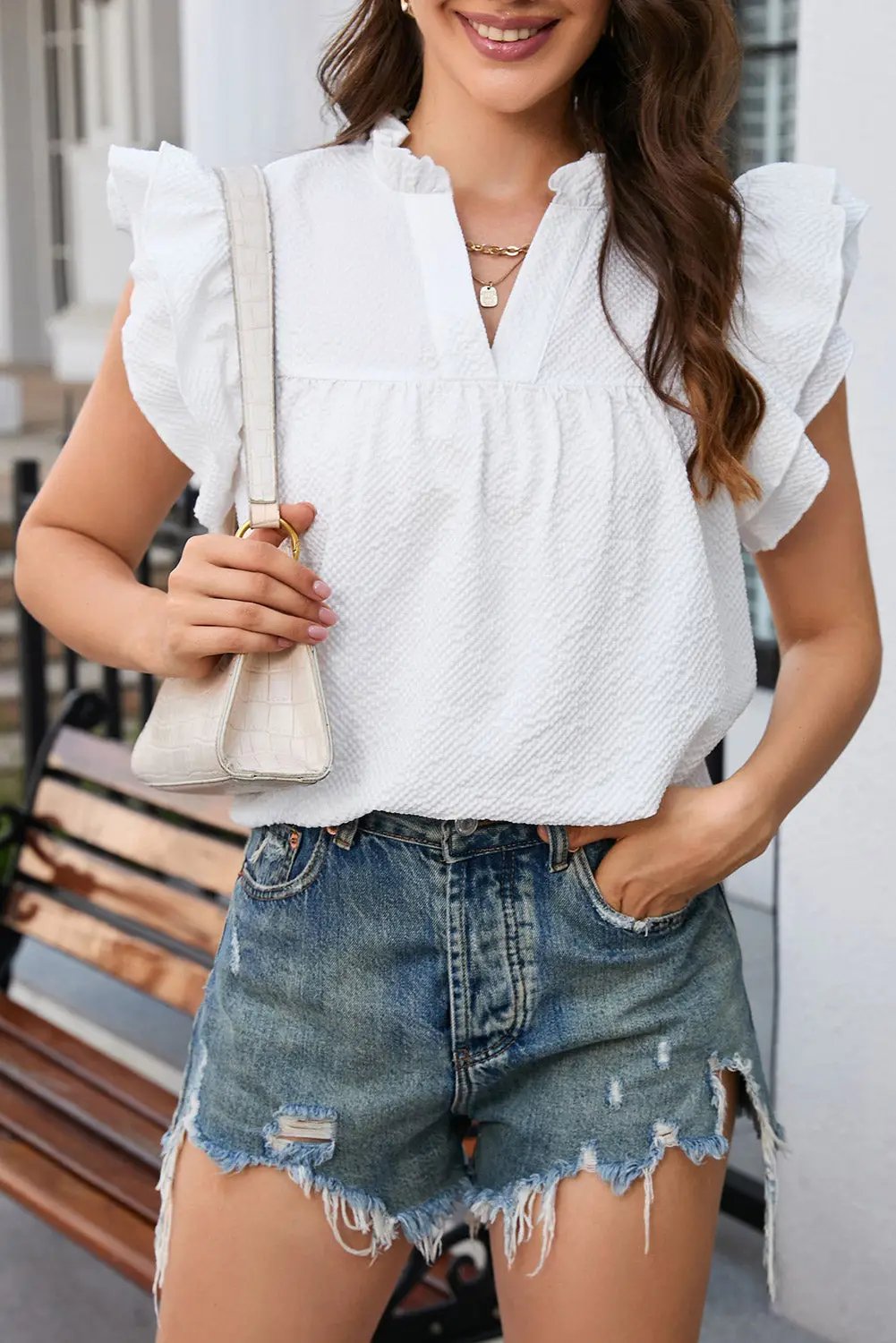 a woman wearing a white top and denim shorts