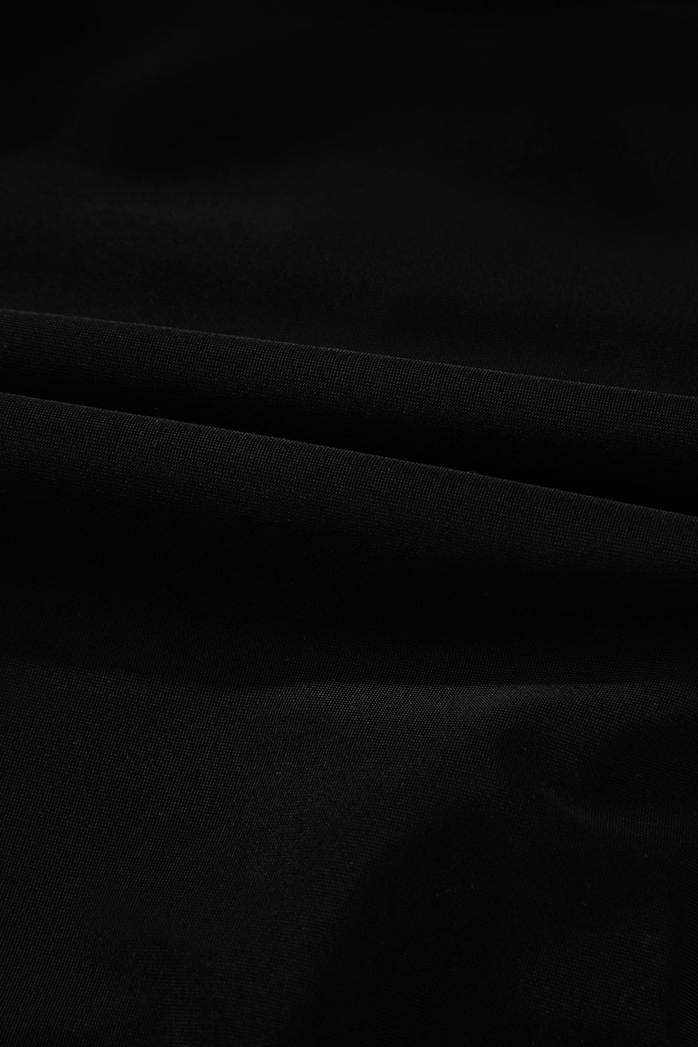 Fabric texture close-up of solid black material used in the 2-tone Crossed Cutout Backless Monokini, soft and stretchable.