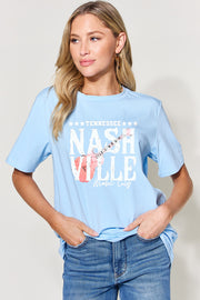 a woman wearing a light blue shirt with the words nashville on it