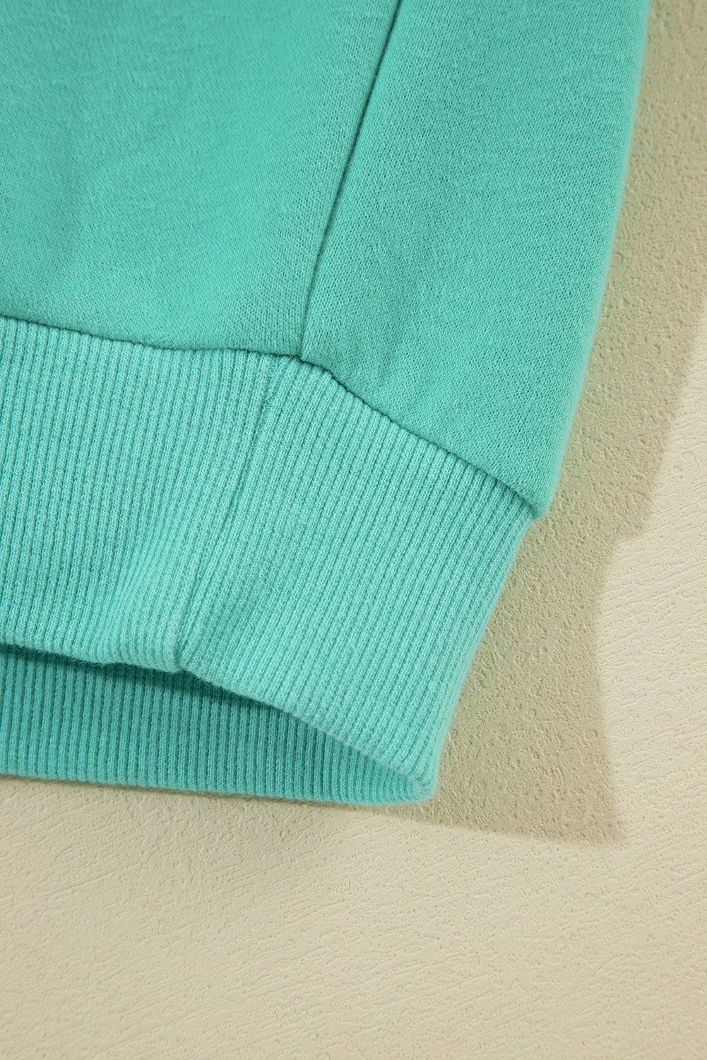 a close up of a green sweater on a white surface