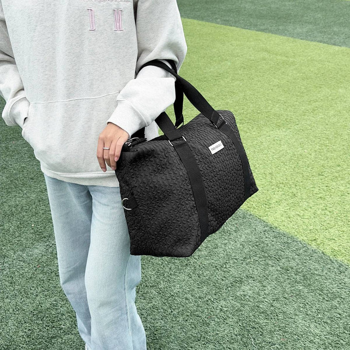 a person holding a black bag on a field