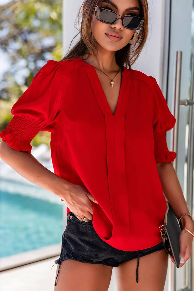 a woman wearing a red blouse and black shorts