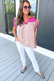 a woman standing on a porch wearing white pants and a pink top