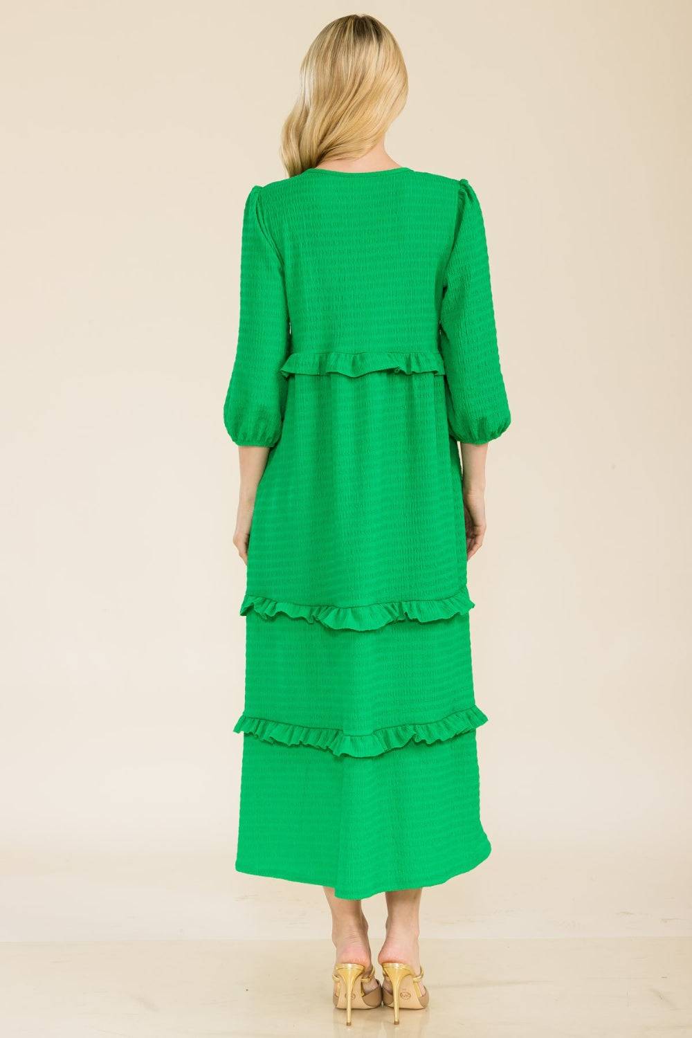 a woman wearing a green dress with tiered layers