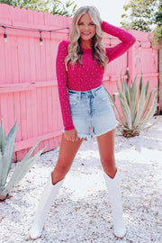 a woman posing in a pink sweater and denim skirt