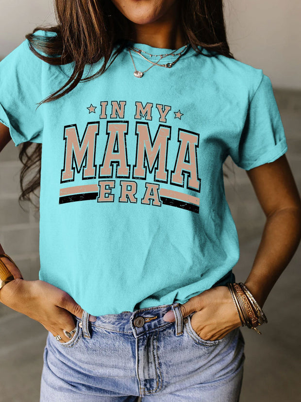 a woman wearing a turquoise shirt that says in my mama era