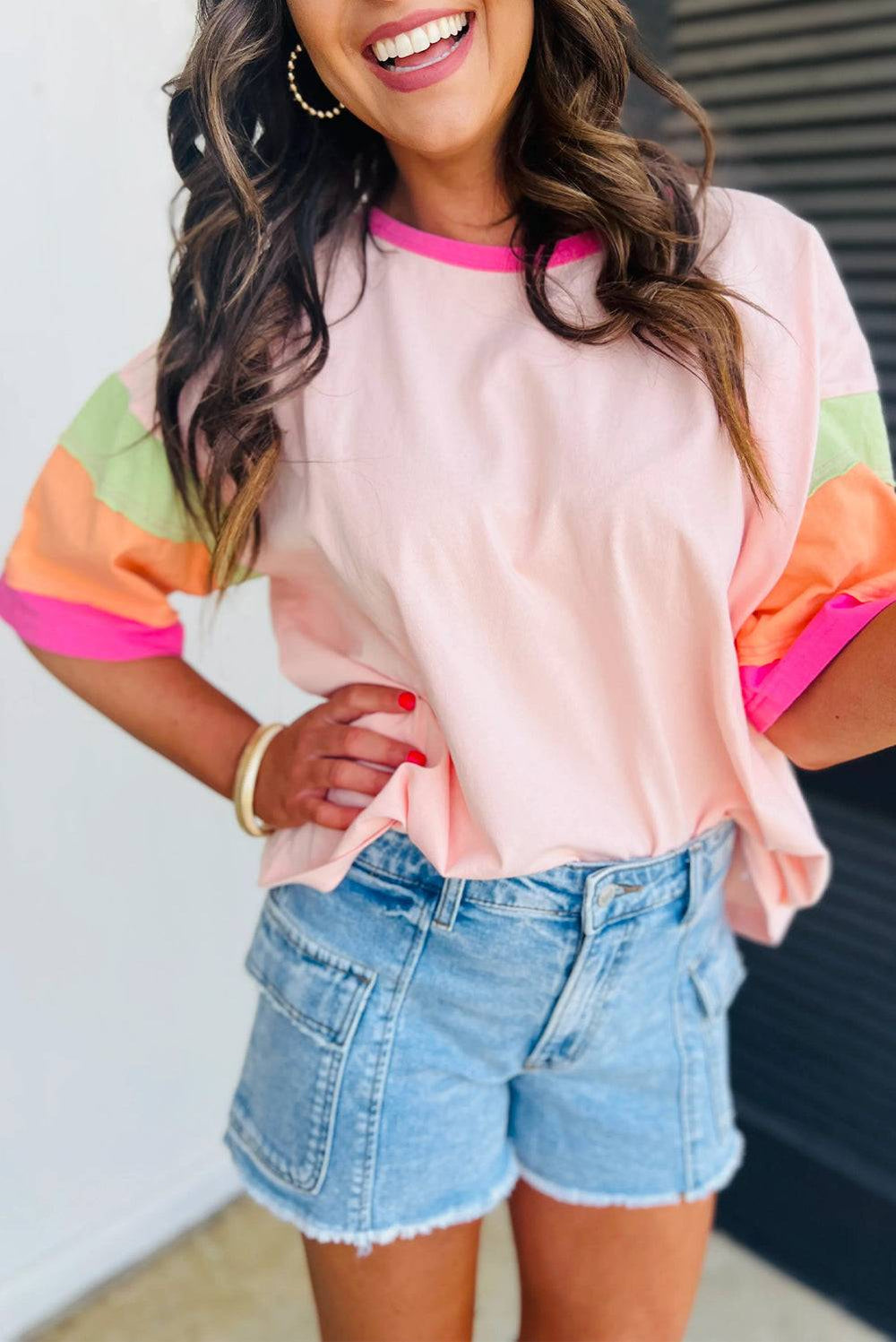 a woman wearing a pink shirt and denim shorts