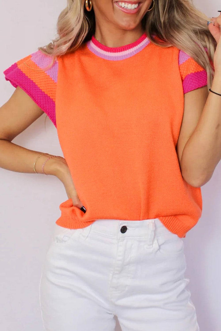 a woman in an orange sweater and white pants