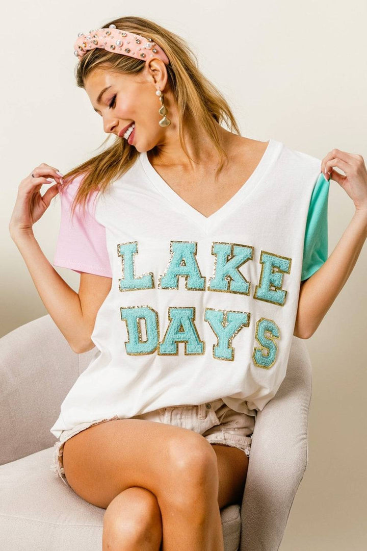 a woman sitting on a chair wearing a shirt that says lake days