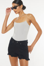 a woman wearing a white tank top and black denim shorts