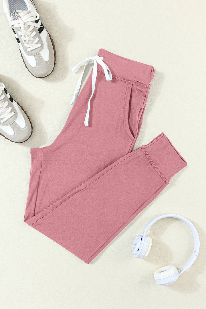 a pair of pink sweatpants, headphones, and a pair of white sneakers