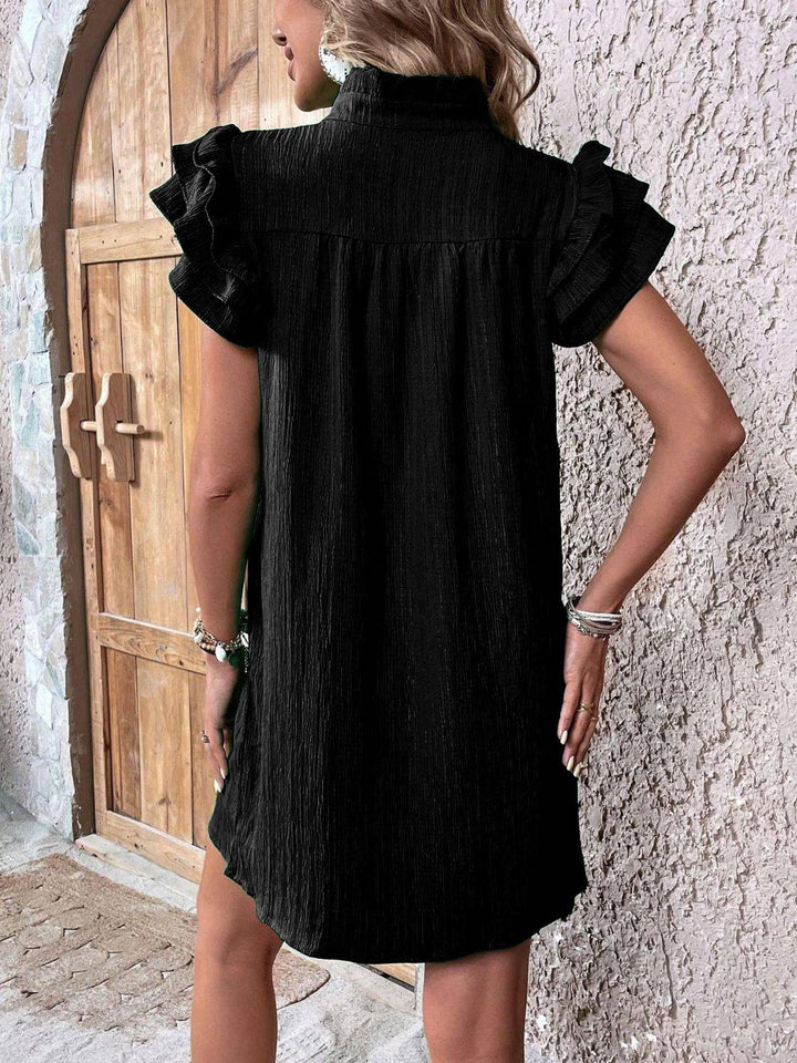 a woman standing in front of a door wearing a black dress