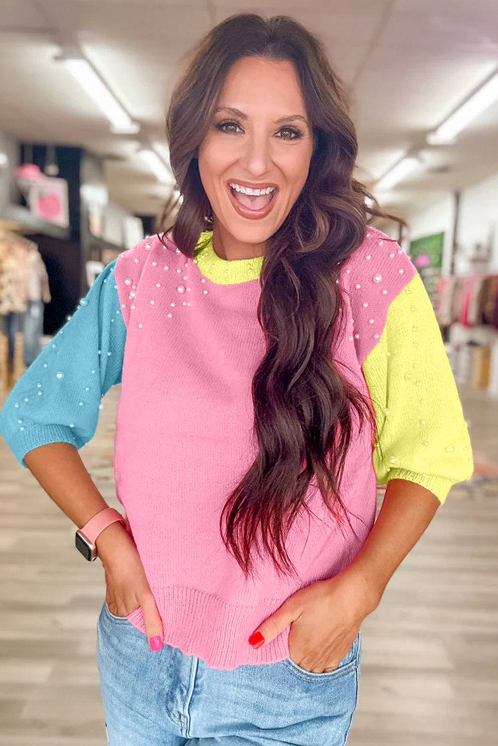 a woman with long hair wearing a pink and blue sweater