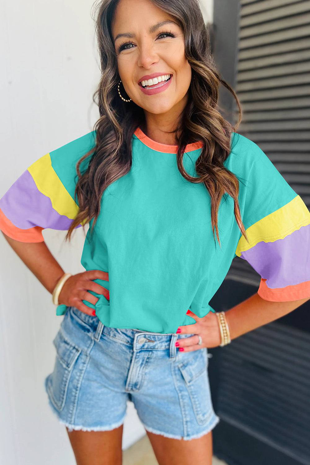 a woman wearing a colorful shirt and denim shorts