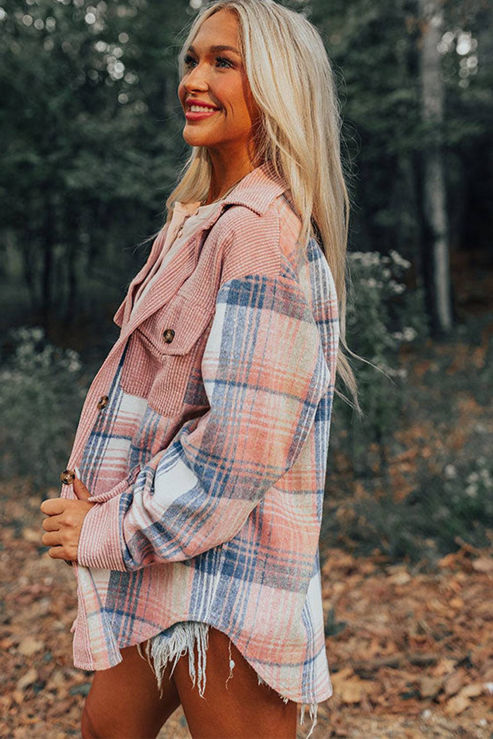 a woman standing in the woods wearing a plaid jacket