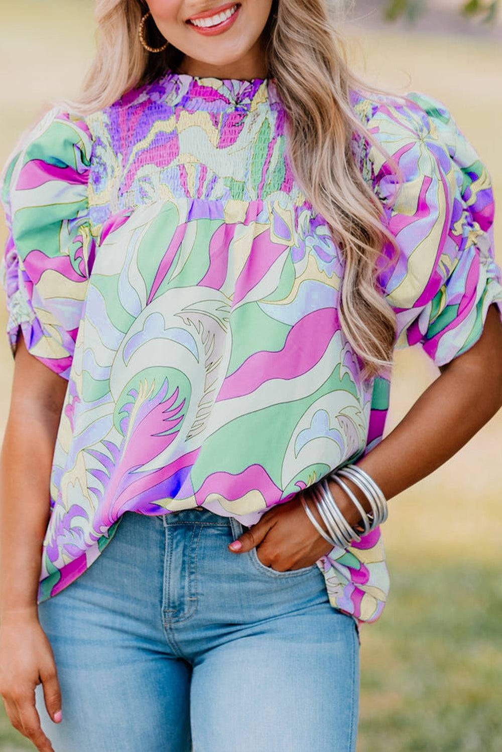 a woman wearing a colorful top and jeans