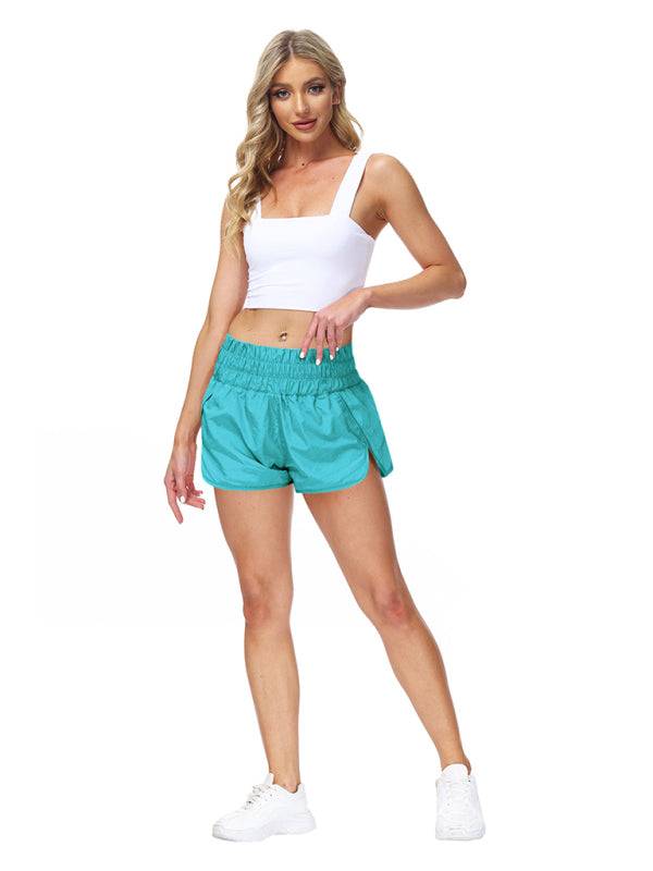 a woman in a white tank top and turquoise shorts