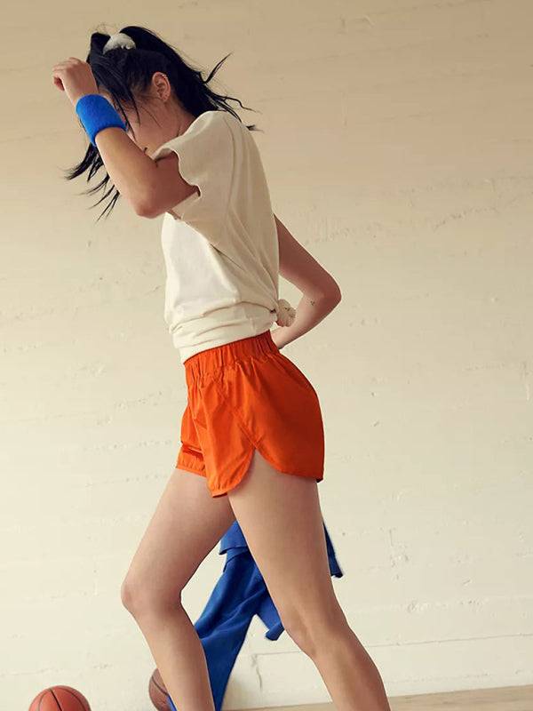 a woman in orange shorts and a white shirt