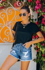 a woman wearing a black shirt and denim shorts