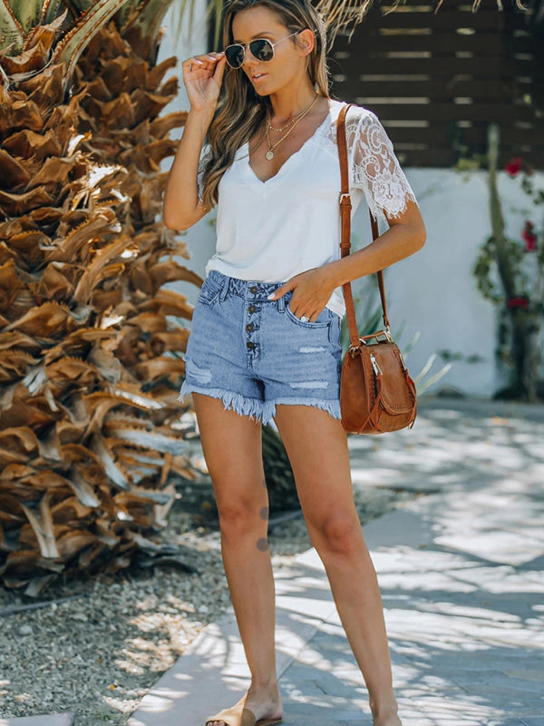 a woman wearing a white top and denim shorts