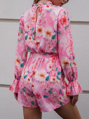 a woman wearing a pink floral romper and shorts