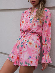 a woman leaning against a wall wearing a pink floral dress