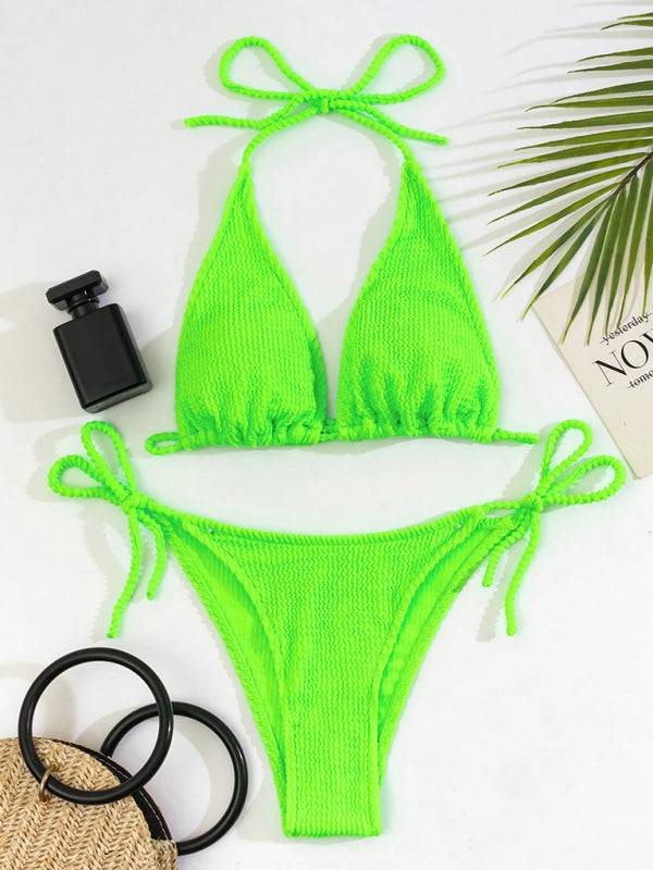a green bikinisuit next to a pair of sunglasses and a camera