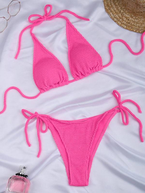a pink bikini top and a pair of glasses on a bed