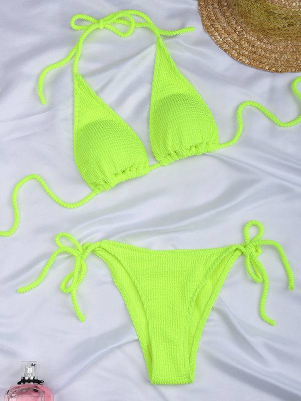 a pair of neon green bikinisuits on a bed