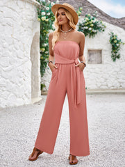 a woman wearing a pink jumpsuit and a hat
