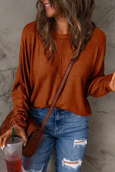 a woman wearing a brown sweater and ripped jeans