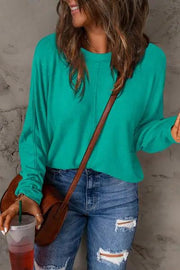 a woman wearing a green sweater and ripped jeans