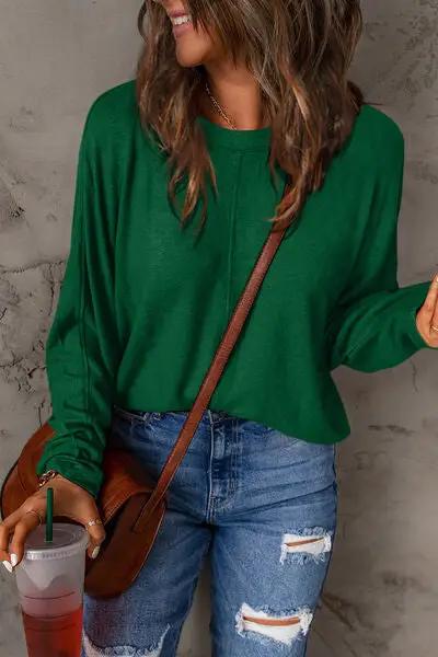 a woman wearing a green sweater and ripped jeans