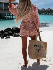 a woman walking on a beach carrying a straw bag